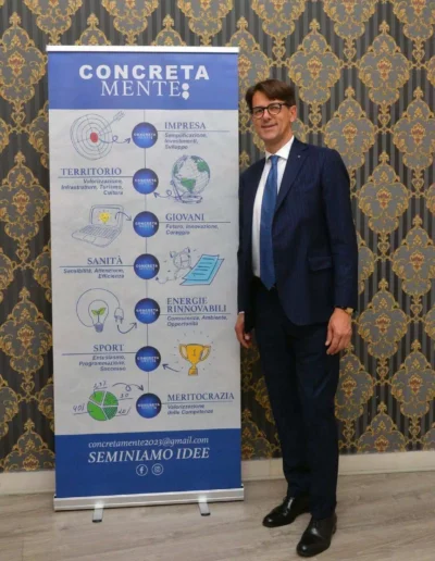 Fabio Lunghi in piedi di fianco al tabellone di Concretamente